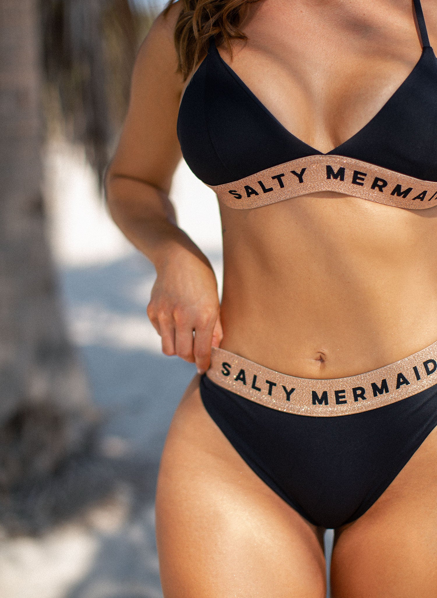 Salty Mermaid signature banded logo bikini in classic Jet Black with rose gold detailing, featuring supportive adjustable straps and high-waisted cheeky bikini bottoms. Stylish and flattering swimwear design with bold branding—perfect for elevated beach looks and luxury resortwear.