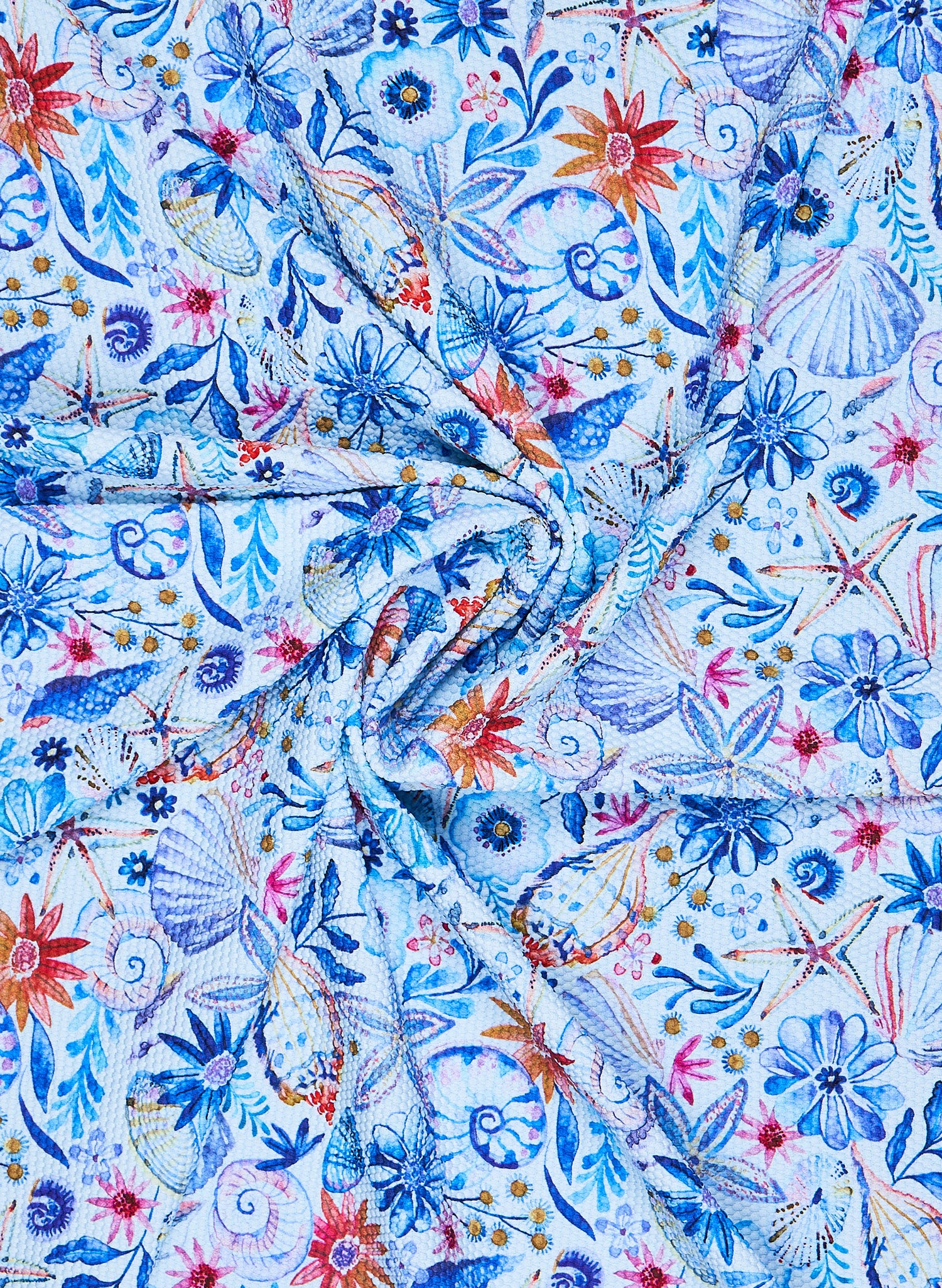 Close-up of Salty Mermaid Nautical Garden print fabric swatch featuring watercolor seashells, coral flowers, and coastal blue botanicals inspired by Nice, France.