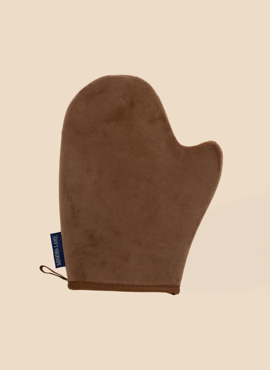 Brown tanning applicator mitt with a blue label on a beige background