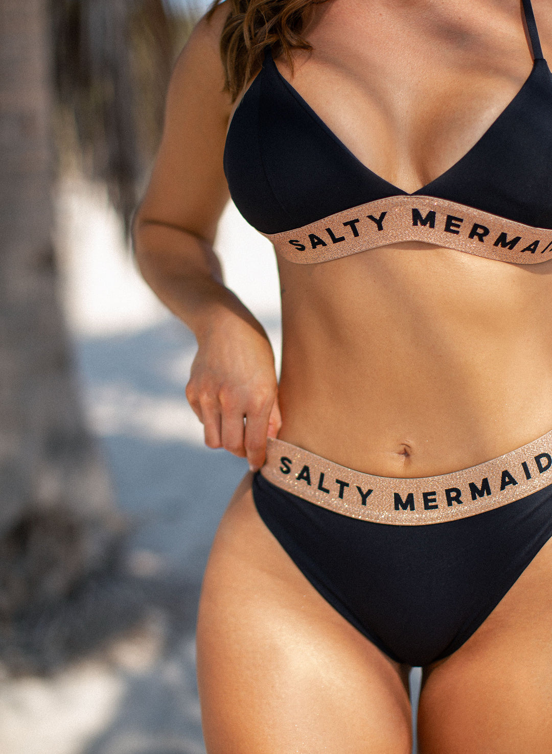 Salty Mermaid signature banded logo bikini in classic Jet Black with rose gold detailing, featuring supportive adjustable straps and high-waisted cheeky bikini bottoms. Stylish and flattering swimwear design with bold branding—perfect for elevated beach looks and luxury resortwear.