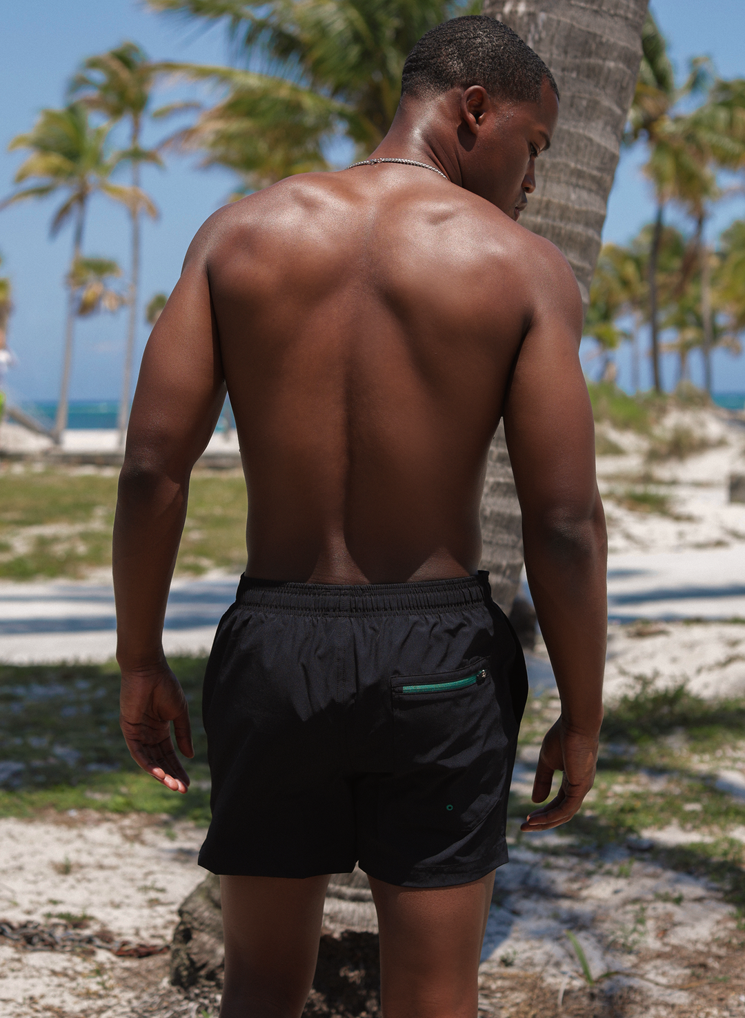 Men’s swim trunks back view with zippered pocket, solid black 5" inseam—Salty Mermaid