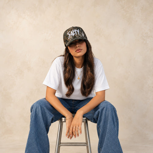 Front view of Salty Mermaid two-tone performance hat with a cream crown, raised white rubber lettering and forest green brim.
