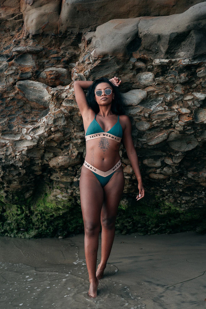 Salty Mermaid signature banded logo bikini in Laguna Green with rose gold accents, featuring supportive adjustable straps and high-hip semi-cheeky bikini bottoms. Bold, sporty swimwear design with flattering fit—perfect for beach days and resort lounging.