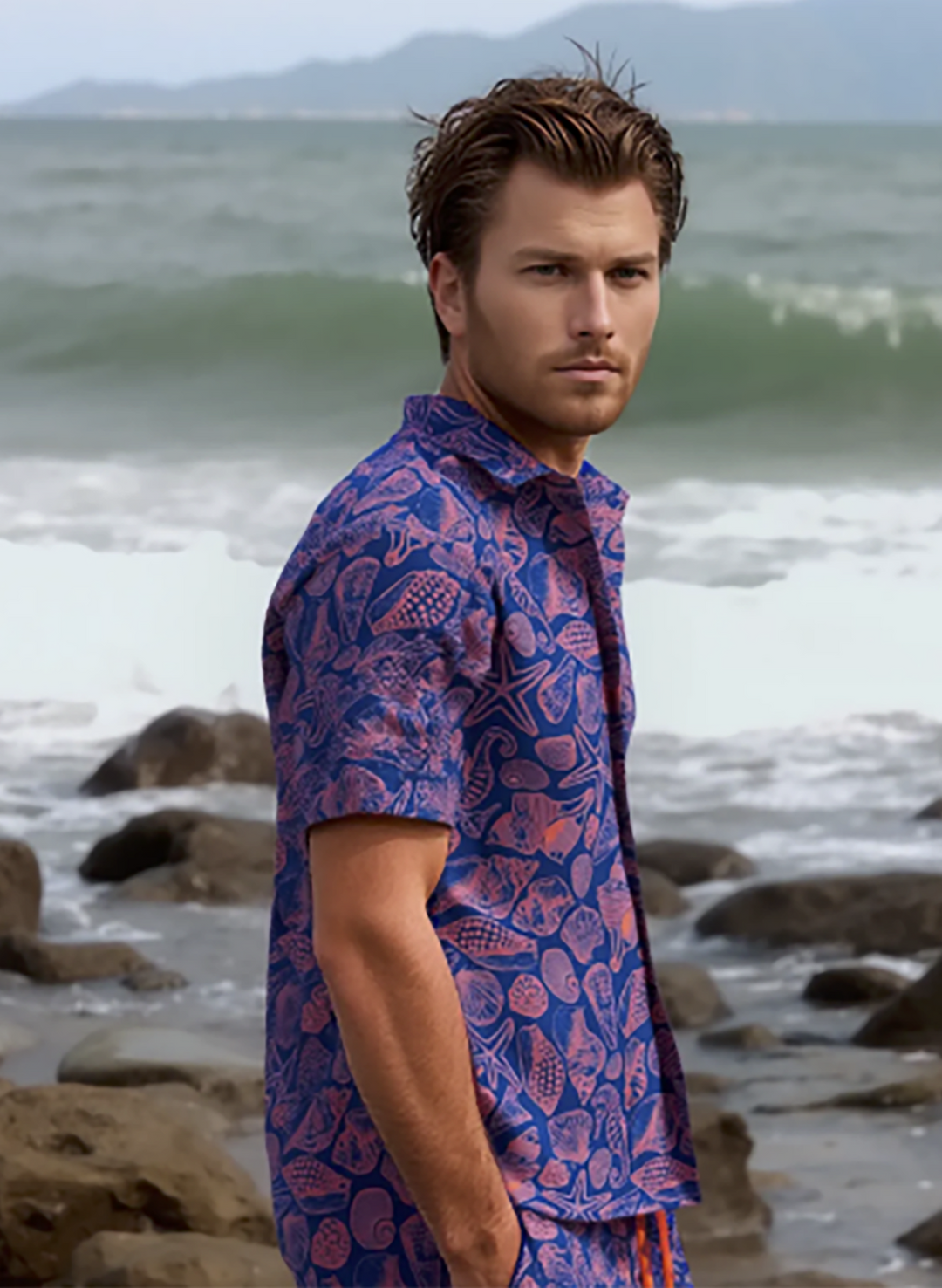 Model wearing Salty Mermaid men's Neon Drift Button down with matching swim trunks. Coral pink & navy shell print.