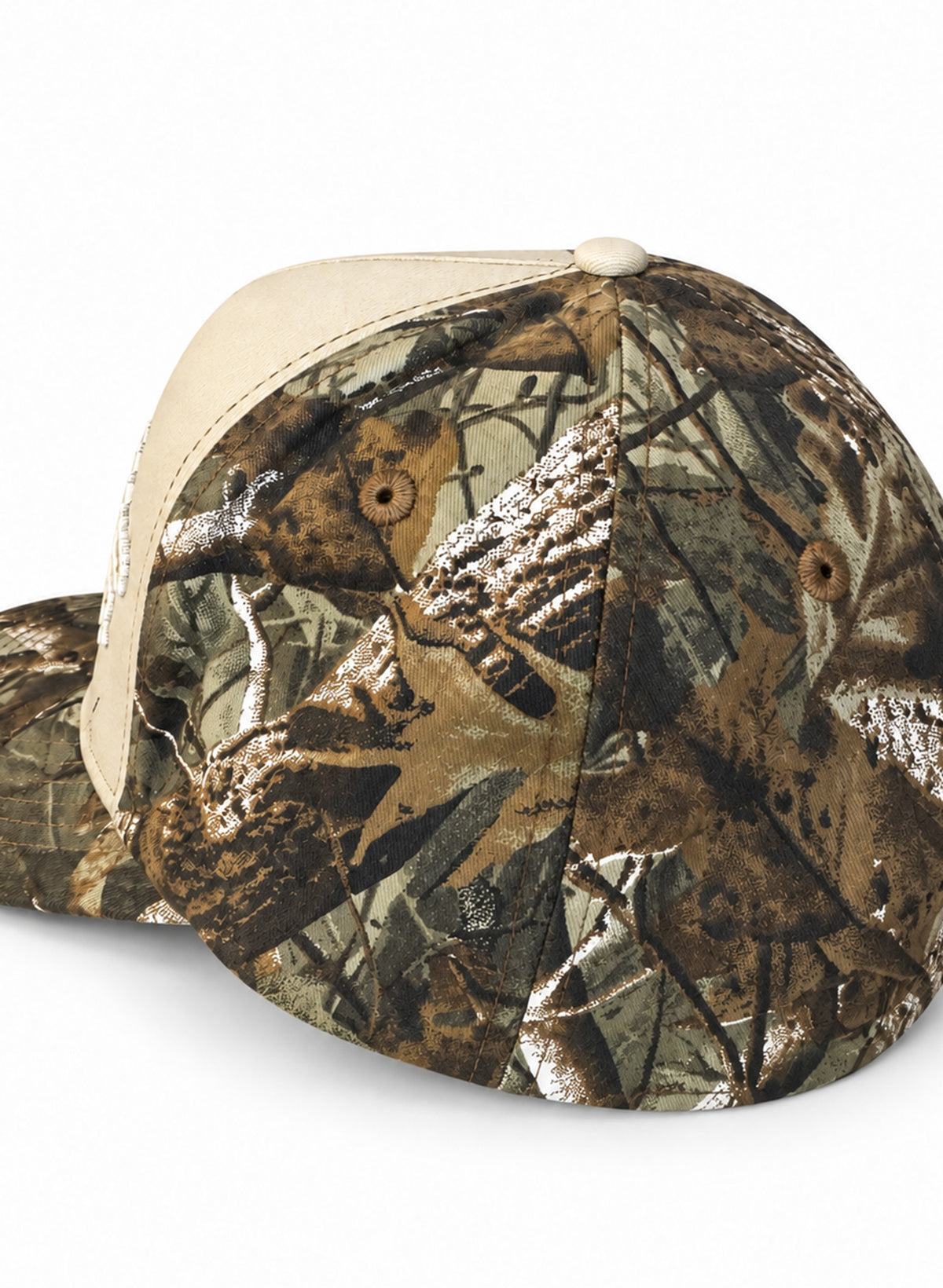 Side view of the Salty Mermaid Dark Woodland camo hat showing the leafy brown and olive crown, embroidered eyelets, and cream front panel on white.
