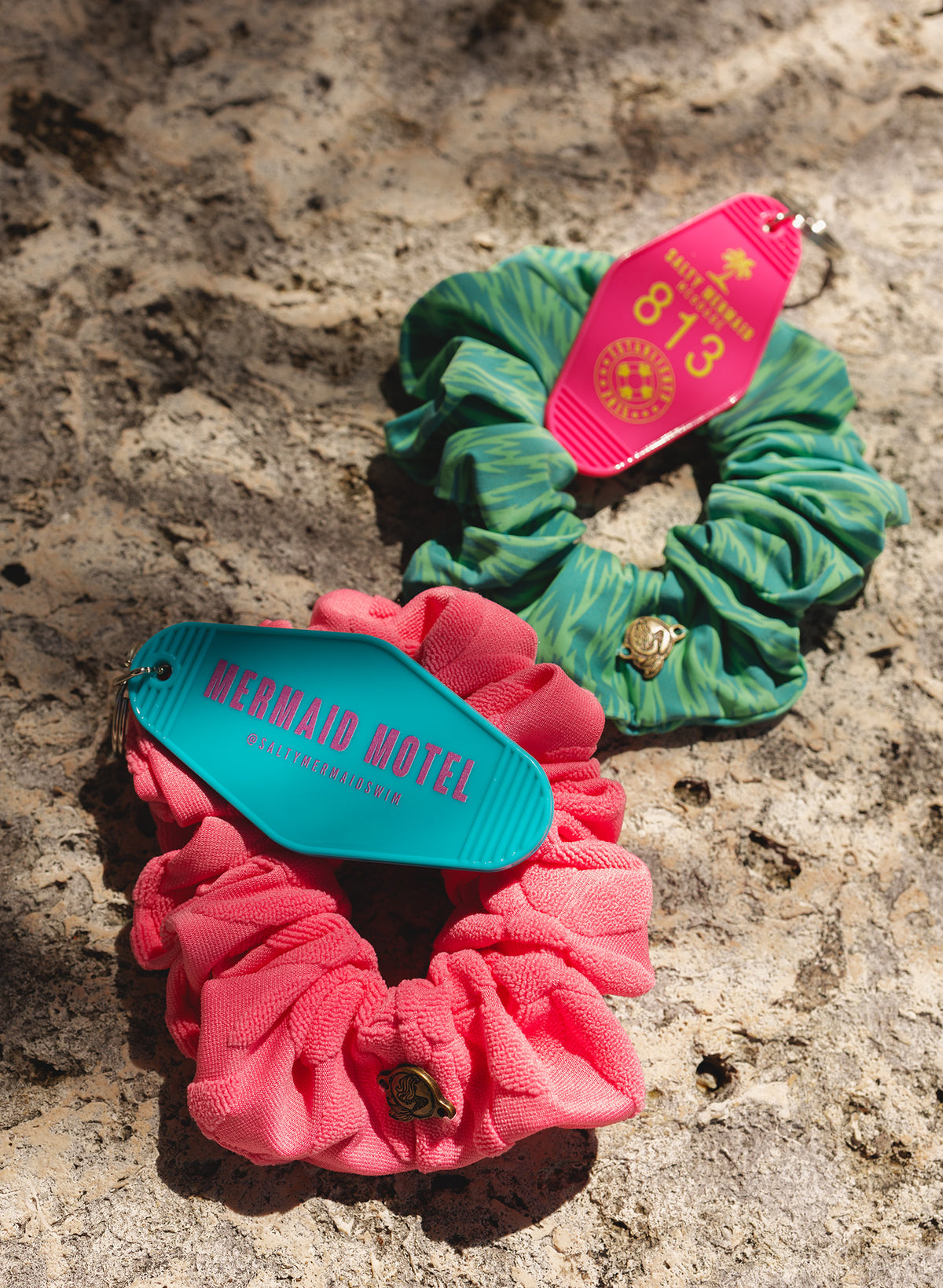 Salty Mermaid Mystery Box preview with pink and green print scrunchies and pink and turquoise motel keychains.