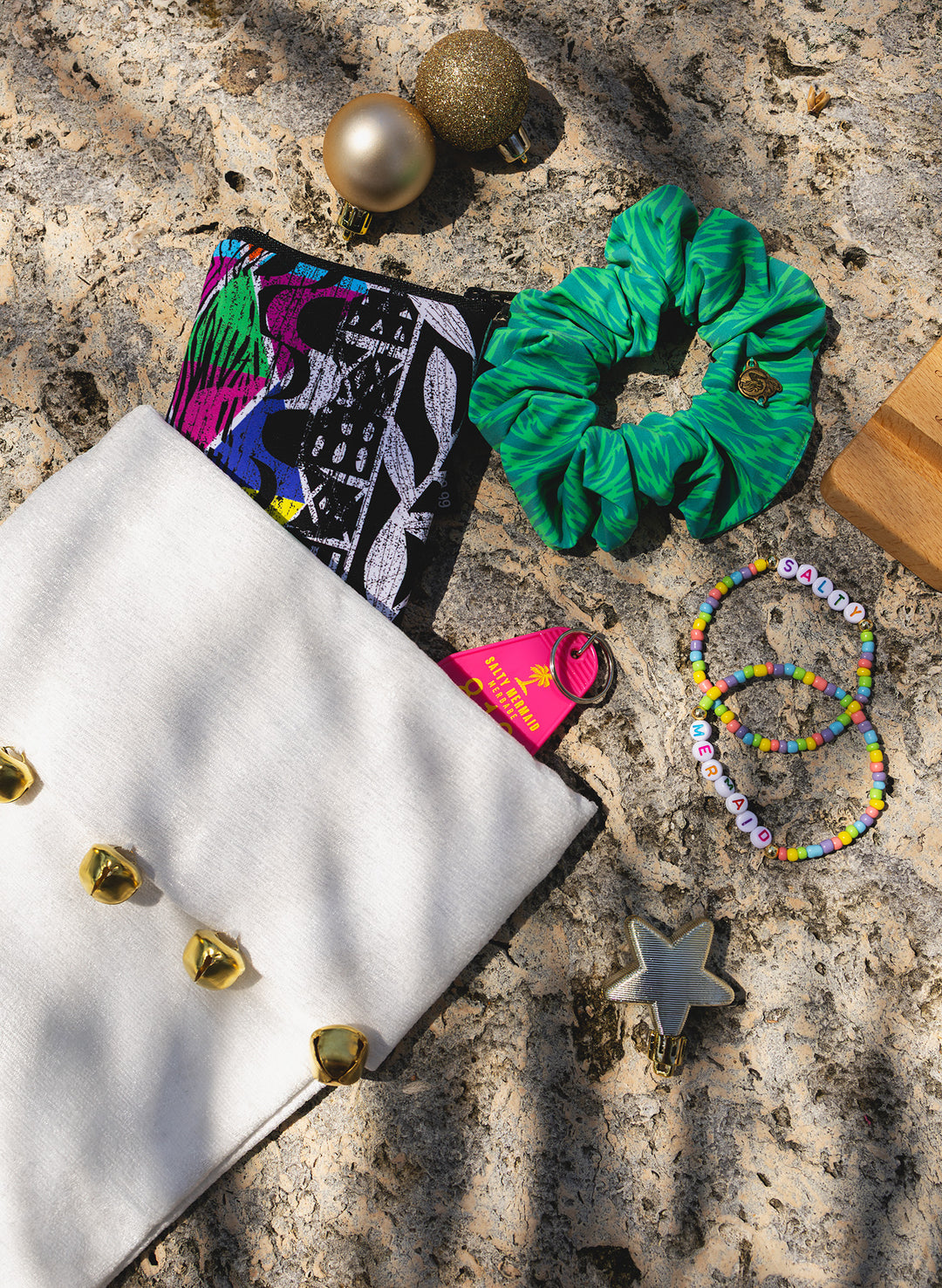 Salty Mermaid Mystery Box preview with a green print scrunchie, colorful zip pouch, pink keychain and beaded friendship bracelets.