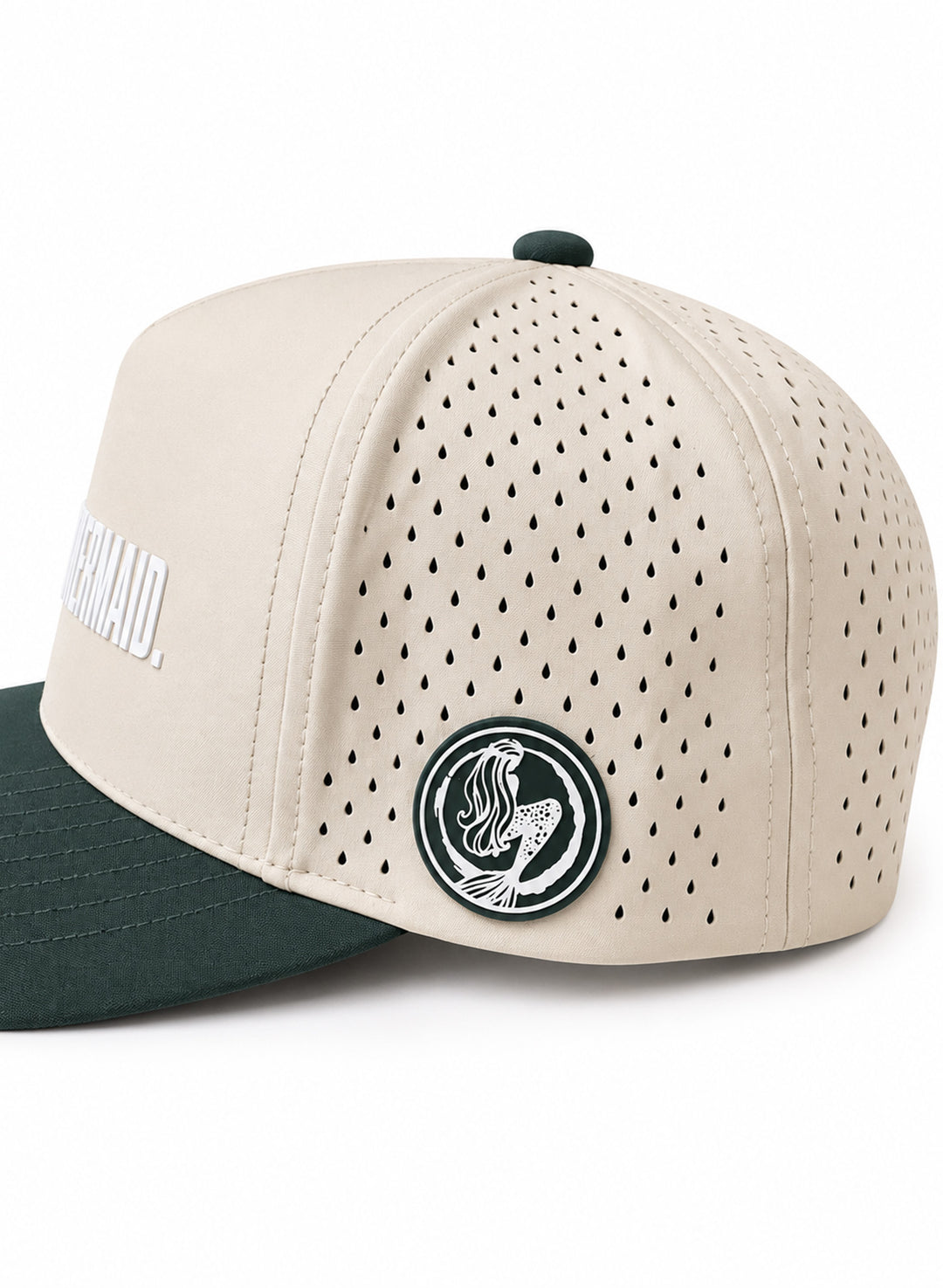 Close-up of Salty Mermaid cream hat with teardrop perforations, a green and white mermaid logo patch and forest green brim.
