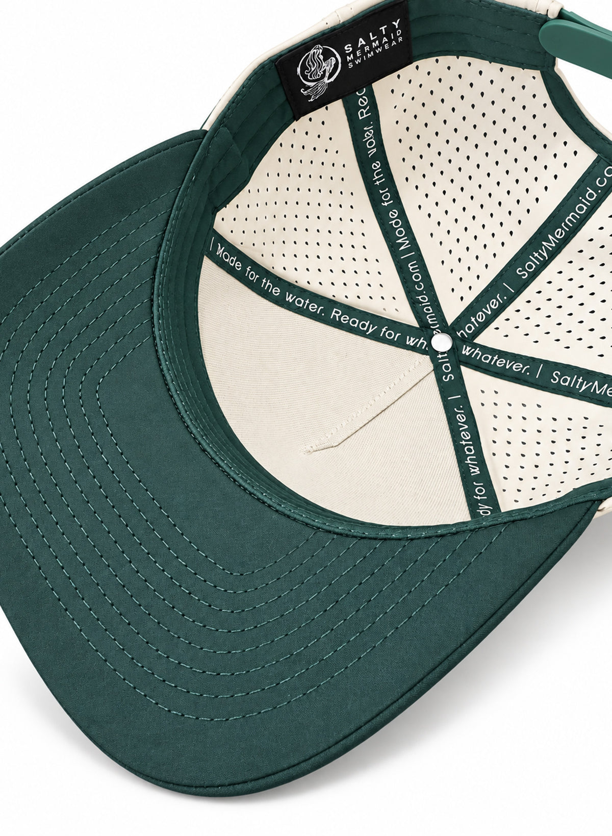 Underside detail of Salty Mermaid performance hat showing the stitched green brim, cream front backing and branded interior taping.

