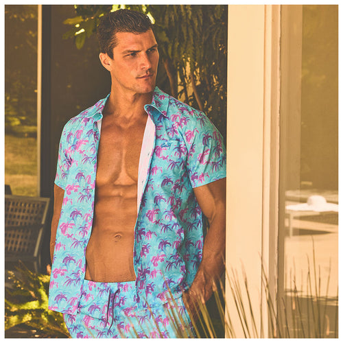 Man wearing a 70s inspired hawaiian floral matching swim trunks and shirt set by salty mermaid hot tropic collection