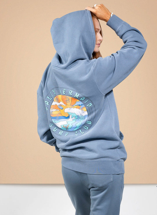 Salty Mermaid slate blue Surf Club hoodie with oversized fit and colorful ocean wave sunset graphic on back