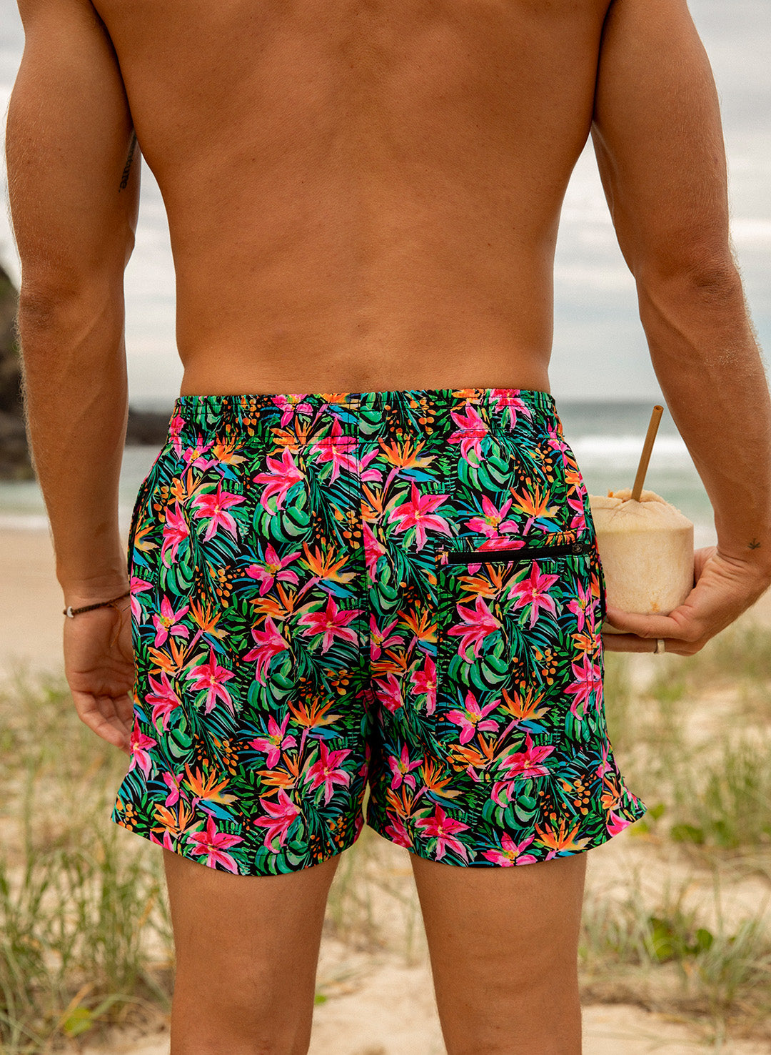 Back view of Island Bloom men’s tropical floral swim trunks, 4–5" inseam, pink and green print with secure zip back pocket, fast-drying 4-way stretch fabric.