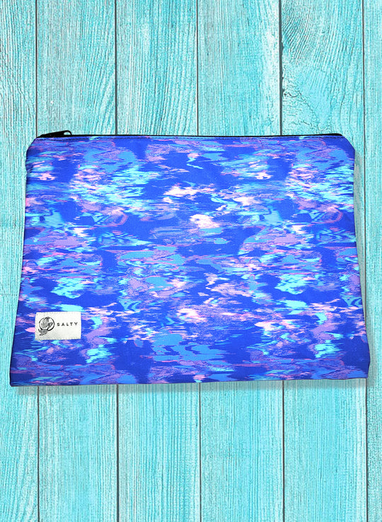 A multicolored spandex blend bikini bag with a zipper closure, displayed against a wooden turquoise background.